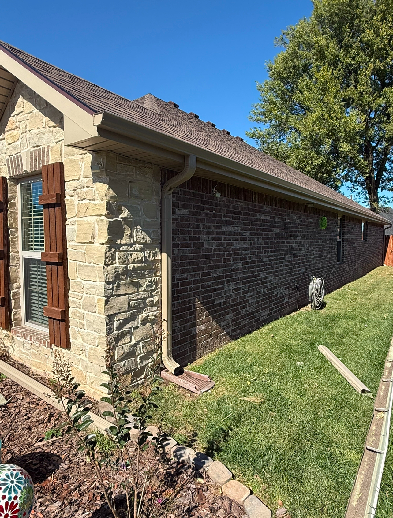 Brick home with seamless gutter and downspout directing rainwater safely away from the foundation