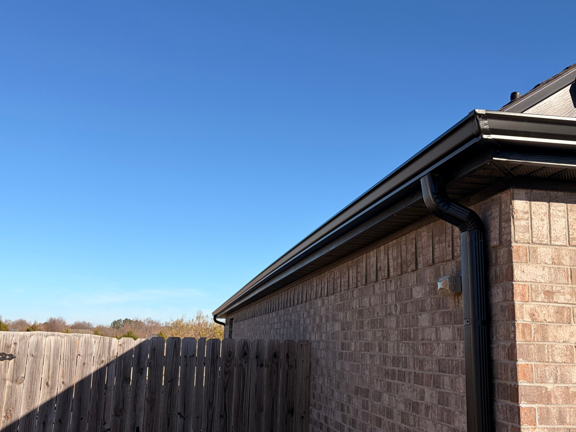 Black seamless gutters and downspout on a brick home in Northwest Arkansas